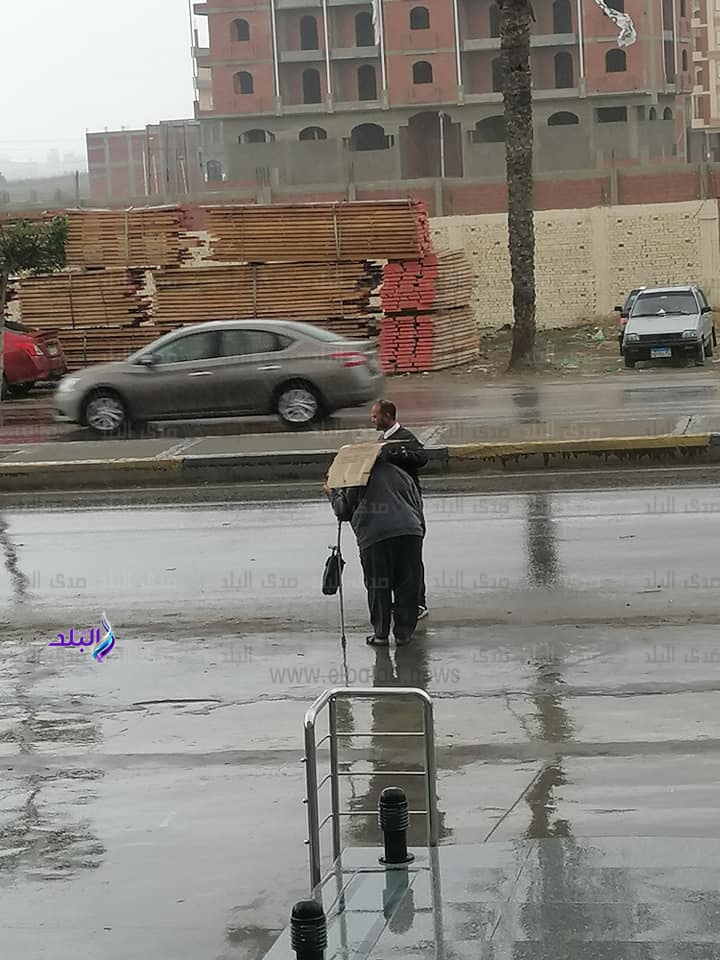 شاب يحمل كرتونة ليحمى مسن