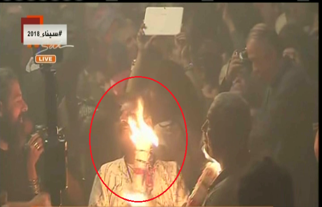 مصلون يمسحون وجوههم بالنار بعد خروج النور المقدس من قبر المس