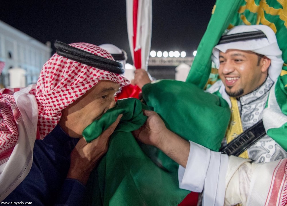 صورة أرشيفية للملك سلمان وهو يقبل العلم السعودي 
