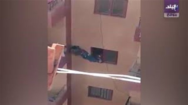 صورة أم تدفع ابنها من النافذة إلى البلكونة