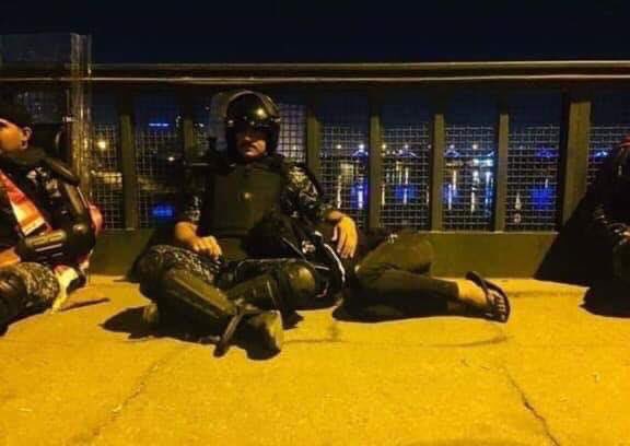 ضابط عراقي يجلس إلى جوار متظاهر