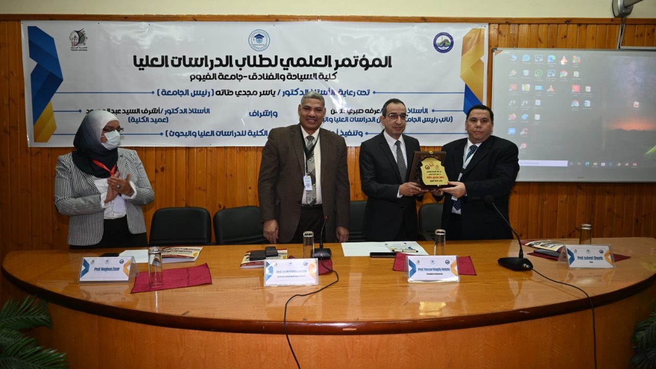 عميد كلية السياحة والفنادق يهدى درع الكلية لرئيس الجامعة