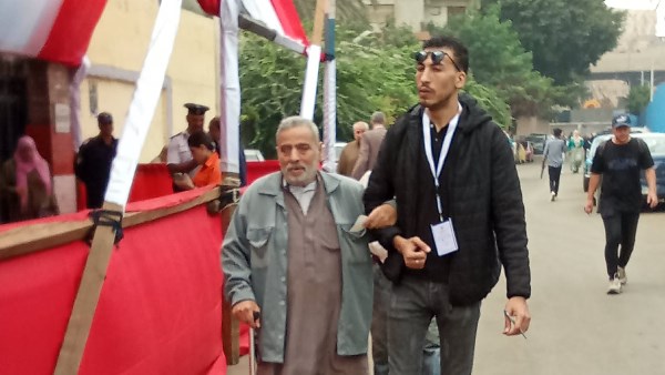 مشهد إنساني بالجيزة شاب يساعد مسنا على الإدلاء بصوته في انتخابات مجلس النواب