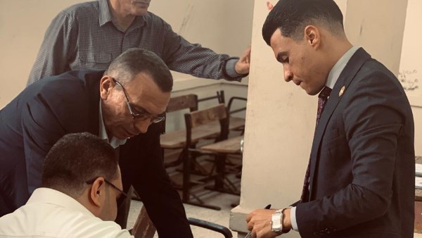 رئيس اللجنة خلال مساعدته شخص كفيف