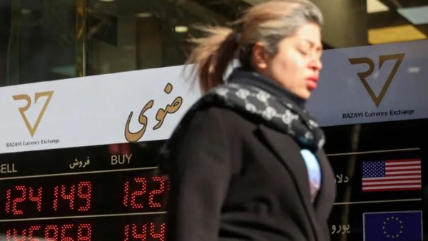 سيدة إيرانية تسير بجوار مصرف بإيران