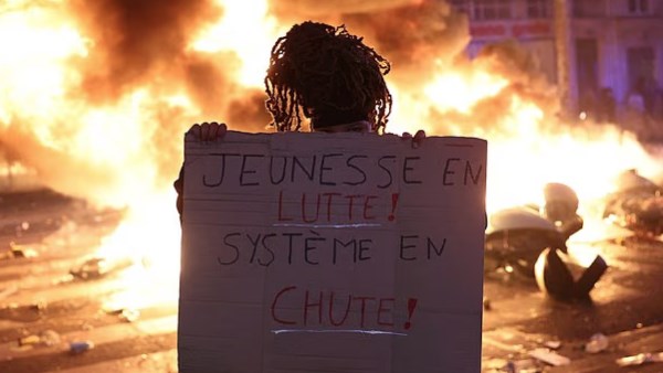 فتاة فرنسية ترفع لافتة تقول "كفاح الشباب من أجل إسقاط النظام"