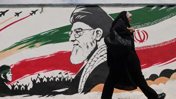 امراة إيرانية تسير بجانب لوحة دعائية مؤيدة للنظام الإيراني