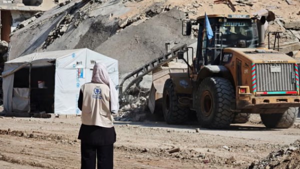 ناشطة تنظر إلى جبل من الركام في غزة